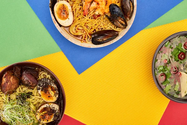 Vista superior de frutos do mar picantes e ramen de carne na superfície multicolorida — Fotografia de Stock