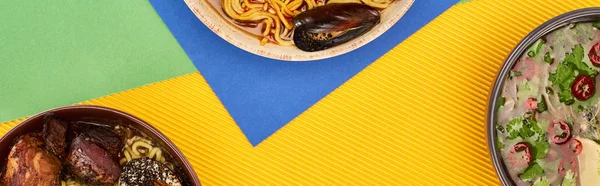 Vista dall'alto di frutti di mare piccanti e ramen di carne su superficie multicolore, colpo panoramico — Foto stock