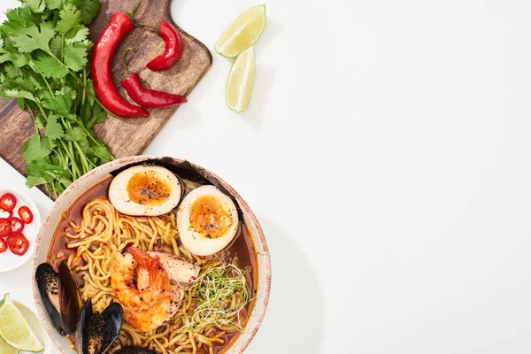 Top view of spicy seafood ramen near fresh ingredients on white surface — Stock Photo