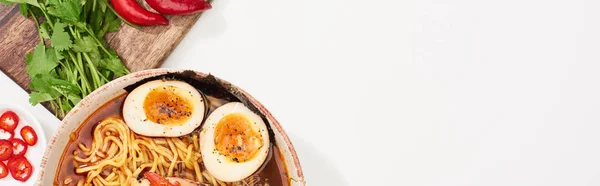 Top view of spicy ramen near fresh ingredients on white surface, panoramic shot — Stock Photo