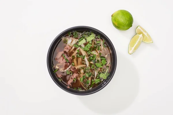 Top view of pho in bowl near lime on white background — Stock Photo