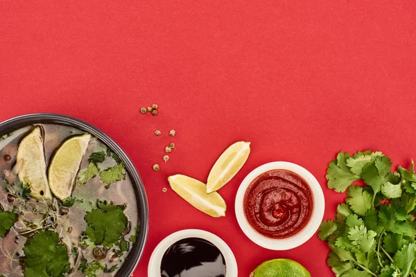 Vue du haut du pho dans un bol près de sauces citron vert, chili et soja et coriandre sur fond rouge — Photo de stock