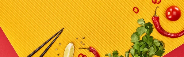 Top view of chopsticks, lime, chili and coriander on red and yellow background, panoramic shot — Stock Photo