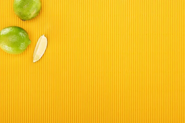 Vue de dessus de citron vert frais sur fond texturé jaune — Photo de stock