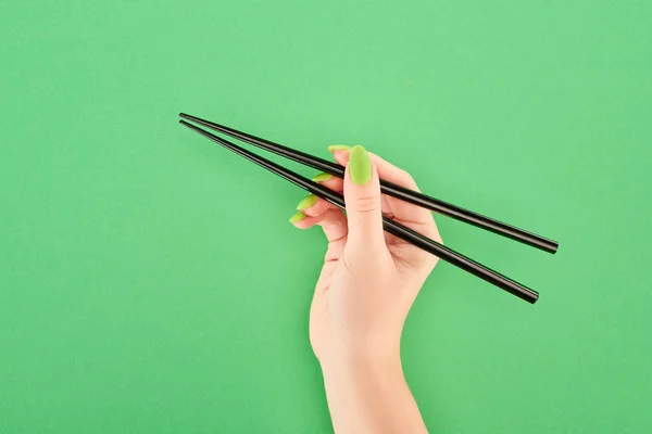 Обрізаний вид жінки, що тримає палички на зеленому фоні — стокове фото