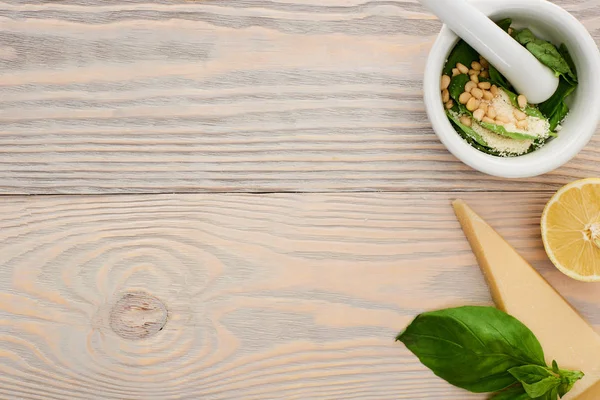 Vue du dessus des ingrédients crus de sauce pesto en livre sur table en bois — Photo de stock