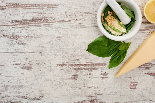 Vue du dessus de la sauce pesto ingrédients crus en livre sur table altérée en bois — Stock Photo