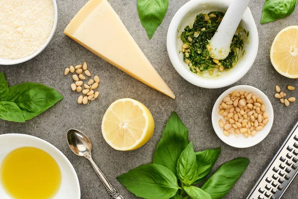 Vue du dessus des ingrédients crus de la sauce pesto et des ustensiles de cuisine sur la surface grise — Stock Photo