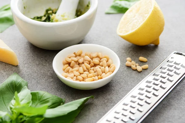 Vista de perto do molho pesto ingredientes crus e utensílios de cozinha na superfície cinzenta — Fotografia de Stock