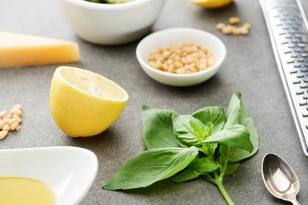 Close up view of pesto sauce raw ingredients and cooking utensils on grey surface — Stock Photo
