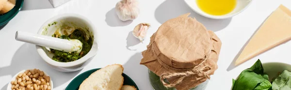 Molho de pesto perto de ingredientes e pão no fundo branco, tiro panorâmico — Fotografia de Stock