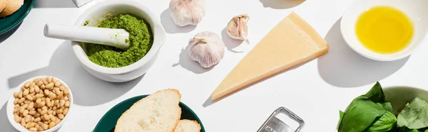 Molho de pesto perto de ingredientes e pão no fundo branco, tiro panorâmico — Fotografia de Stock