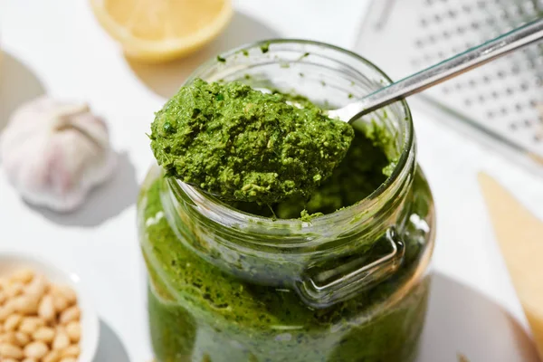 Close up view of pesto sauce in jar with spoon — Stock Photo