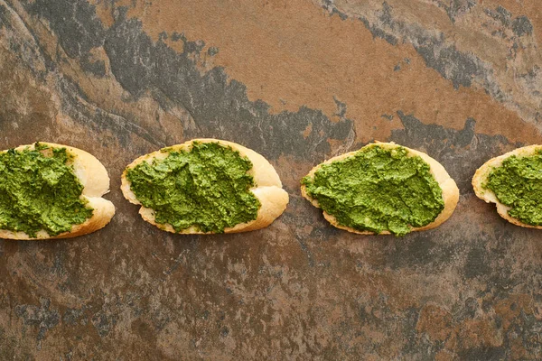 Flat lay with baguette slices with delicious pesto sauce on stone surface — Stock Photo