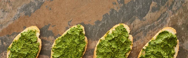 Flat lay com fatias de baguete com delicioso molho pesto na superfície de pedra, tiro panorâmico — Fotografia de Stock