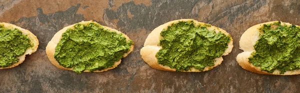 Plat étendu avec des tranches de baguette avec une délicieuse sauce pesto sur la surface de la pierre, vue panoramique — Photo de stock