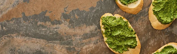 Top view of baguette slices with delicious pesto sauce on stone surface, panoramic shot — Stock Photo