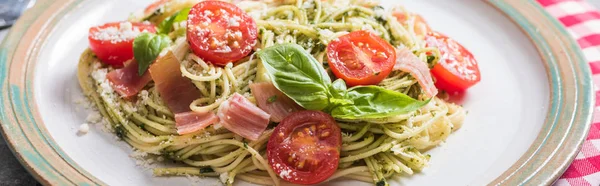 Pappardelle with tomatoes, basil and prosciutto on grey surface with plaid napkin, panoramic shot — Stock Photo