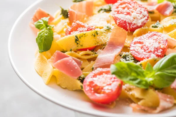 Close up view of delicious Pappardelle with tomatoes, Parmesan, pesto sauce, basil and prosciutto — Stock Photo