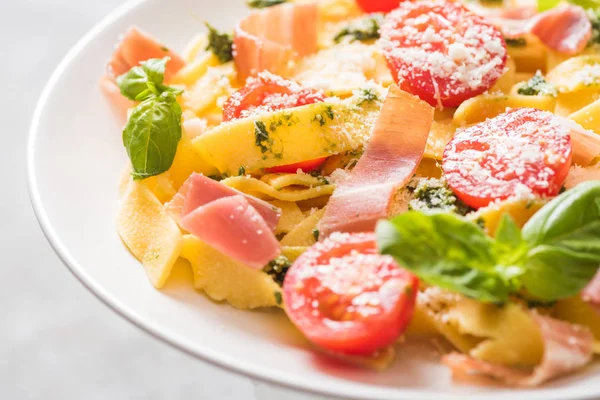 Закрыть вид на вкусный Pappardelle с помидорами, пармезан, соус песто, базилик и прошутто — стоковое фото