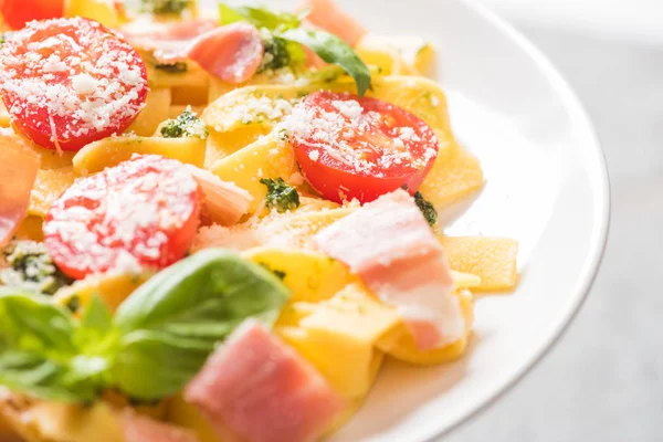 Закрыть вид на вкусный Pappardelle с помидорами, пармезан, соус песто, базилик и прошутто — стоковое фото