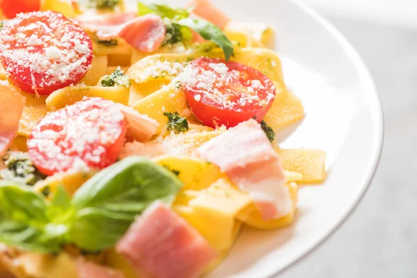 Vista de perto do delicioso Pappardelle com tomates, parmesão, molho pesto, manjericão e presunto — Fotografia de Stock