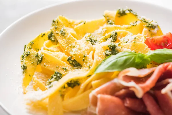 Close up view of delicious Pappardelle with tomatoes, Parmesan, pesto sauce, basil and prosciutto — Stock Photo