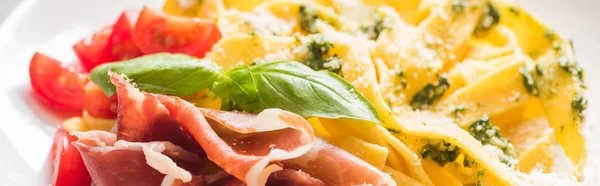 Close up view of delicious Pappardelle with tomatoes, Parmesan, pesto sauce, basil and prosciutto, panoramic shot — Stock Photo