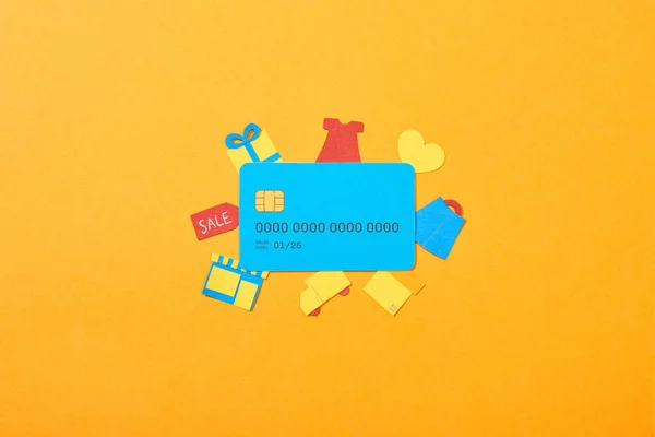 Vista superior de la plantilla de tarjeta de crédito azul cerca de iconos de compras aislados en naranja - foto de stock