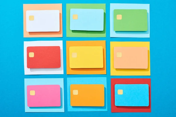 Vista superior de tarjetas de crédito vacías multicolores sobre fondo azul - foto de stock