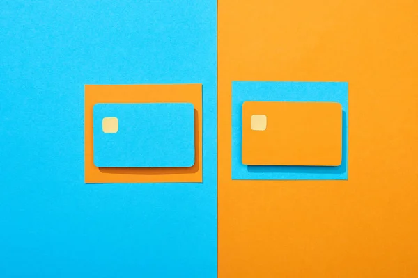 Vue de dessus des cartes de crédit vides colorées sur fond bleu et orange — Photo de stock