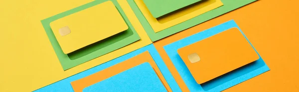 Tarjetas de crédito vacías sobre fondo verde, naranja, azul y amarillo, plano panorámico - foto de stock
