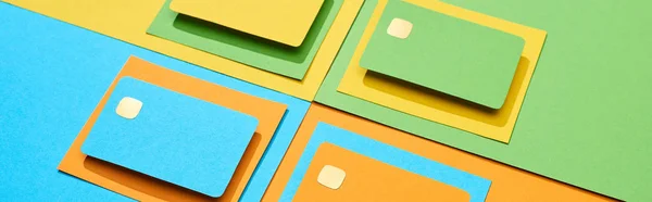 Cartes de crédit vides sur fond vert, orange, bleu et jaune, panoramique — Photo de stock