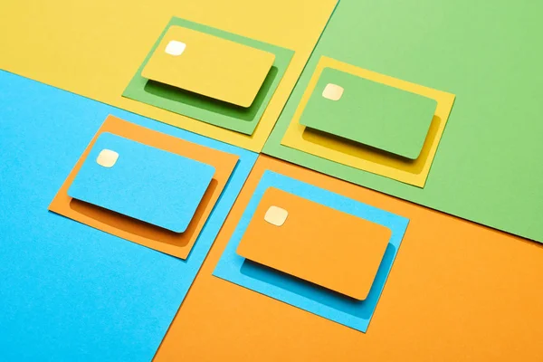 Tarjetas de crédito vacías sobre fondo verde, naranja, azul y amarillo - foto de stock