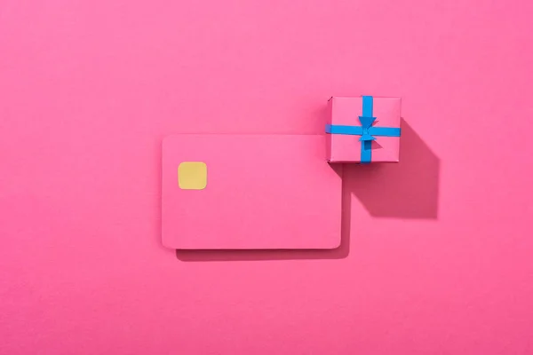 Vista superior de la colorida tarjeta de crédito vacía con caja de regalo sobre fondo rosa - foto de stock