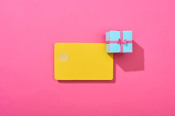 Вид сверху на желтую пустую кредитную карту с подарочной коробкой на розовом фоне — стоковое фото