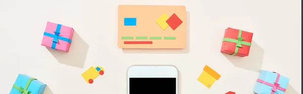 Vue du dessus du modèle de carte de crédit près des icônes, des cadeaux et du smartphone sur fond blanc, vue panoramique — Photo de stock