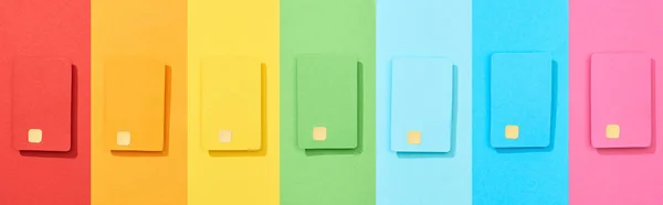 Top view of multicolored empty credit cards on rainbow background, panoramic shot — Stock Photo