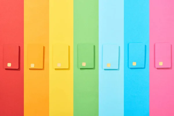 Vista dall'alto di carte di credito vuote multicolori su sfondo arcobaleno — Foto stock
