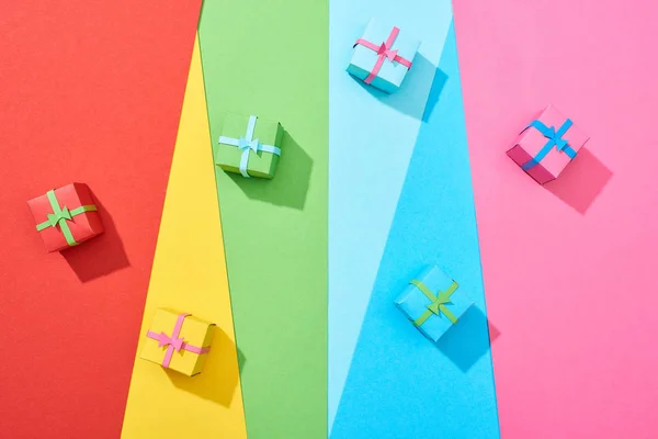 Vista dall'alto di scatole regalo multicolore sparse su sfondo arcobaleno — Foto stock