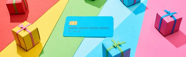 Cartão de crédito vazio e caixas de presente multicoloridas no fundo do arco-íris, tiro panorâmico — Fotografia de Stock