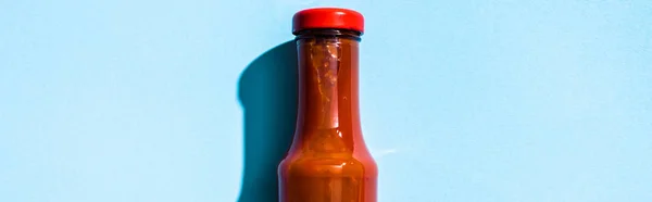 Vista superior da garrafa com ketchup em fundo azul, tiro panorâmico — Fotografia de Stock