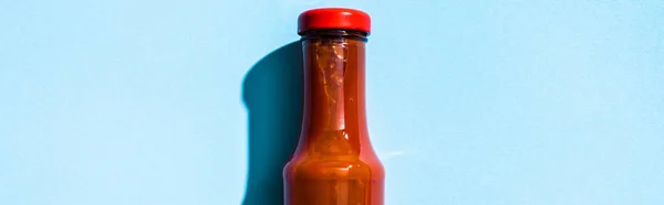 Top view of bottle with ketchup on blue background, panoramic shot — Stock Photo