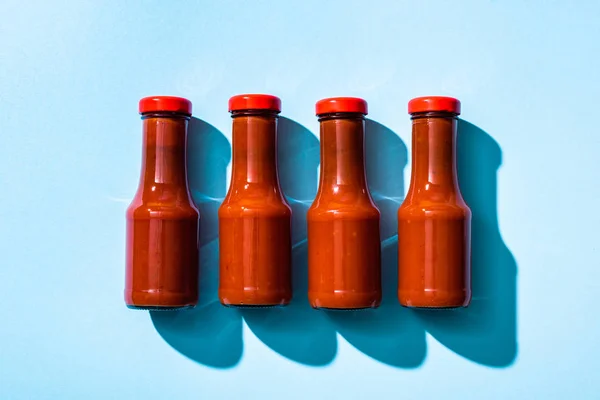 Vue du dessus du ketchup en bouteilles sur fond bleu — Photo de stock