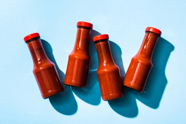 Vue du dessus de la sauce tomate en bouteilles avec ombre sur fond bleu — Photo de stock