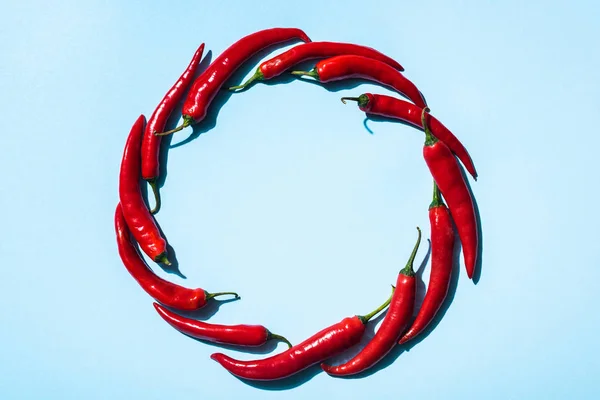 Top view of round frame of chili peppers on blue surface — Stock Photo