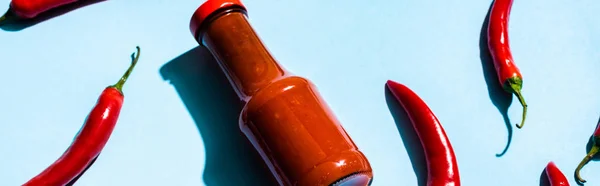 Chili sauce with chili peppers on blue background, panoramic shot — Stock Photo