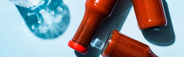 Vista superior de vidro de água e garrafas com ketchup em fundo azul, tiro panorâmico — Fotografia de Stock