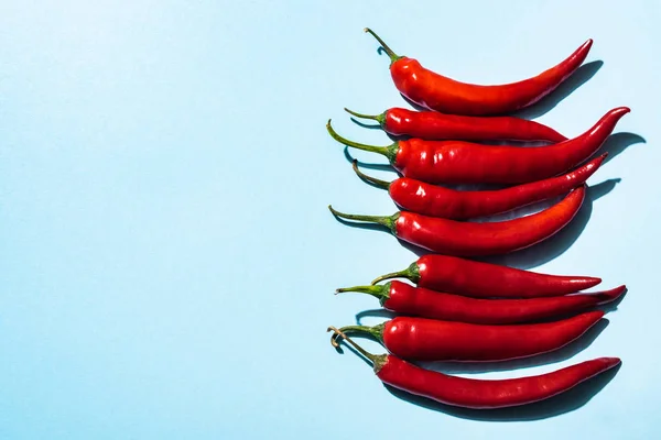 Top view of ripe chili peppers on blue surface — Stock Photo