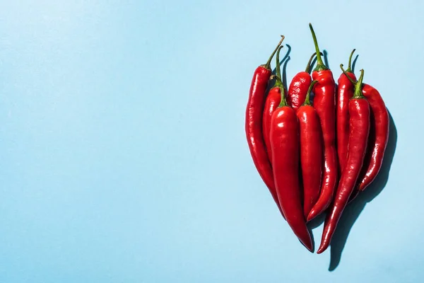 Vue du dessus des piments frais bio sur fond bleu — Photo de stock